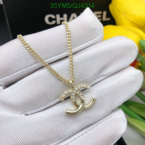 Gold pendant on white glove, yellow flowers background.