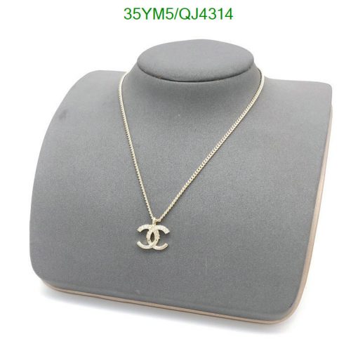 Gold pendant necklace on gray display stand.