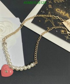 Gold chain pearl bracelet with heart charm on designer stationery.