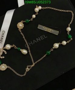 Elegant pearl and emerald gold necklace on black background.