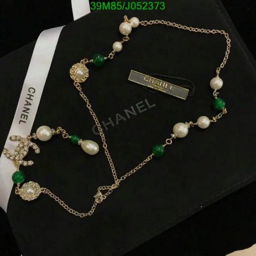 Elegant pearl and emerald gold necklace on black background.