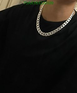 Person wearing black T-shirt and silver chain necklace.