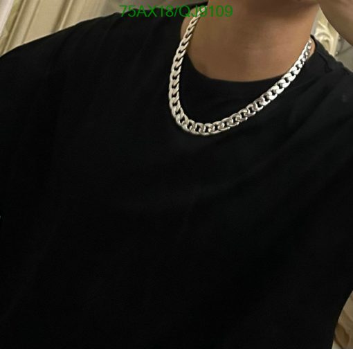 Person wearing black T-shirt and silver chain necklace.