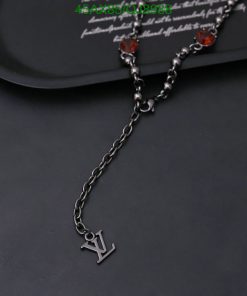 Silver necklace with red gemstones on dark background.