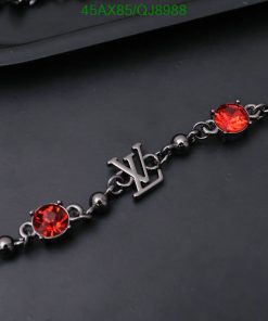 Red gemstone bracelet with initial charm on dark background.