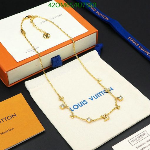 Designer gold-tone necklace on branded display packaging.