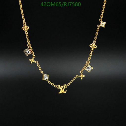 Gold necklace with diamond accents and designer initials.