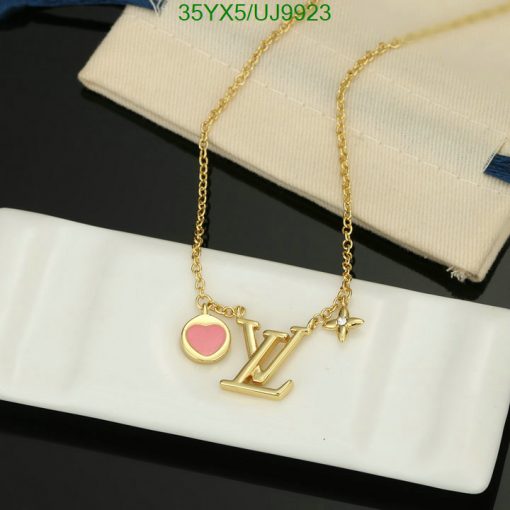 Gold pendant necklace with heart and letters on display.