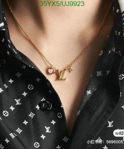 Gold LV logo necklace on patterned blouse.