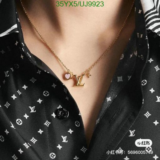 Gold LV logo necklace on patterned blouse.