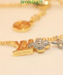 Gold designer logo necklace with flower and sparkle detail.