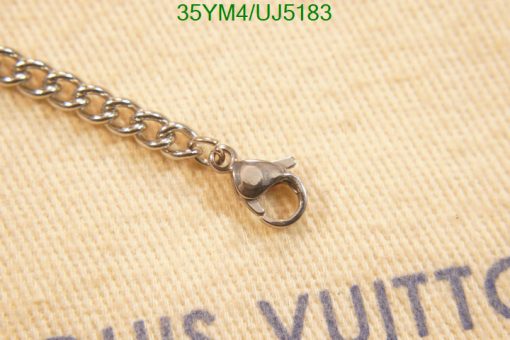 Silver clasp of chain on beige fabric background.