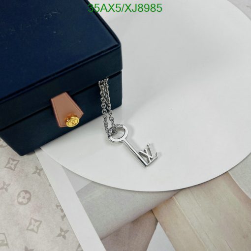 Designer key pendant necklace beside luxury box.