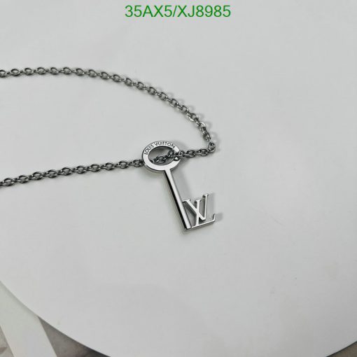 Silver key-shaped pendant necklace on white surface.