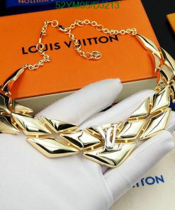 Gold designer necklace on display with branded box.