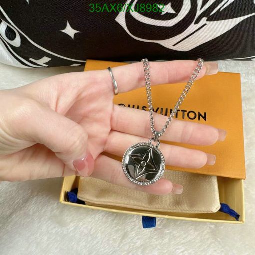 Hand displaying designer pendant necklace with packaging.