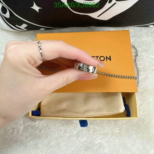 Hand holding designer wallet with chain, packaging visible.