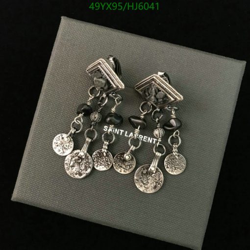 Saint Laurent silver charm earrings on gray background.