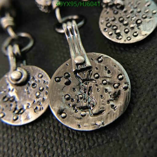 Textured silver earrings on black background.