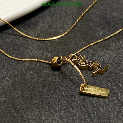 Gold necklace with designer pendant on dark background.