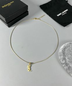 Gold necklace with pendant on white surface.