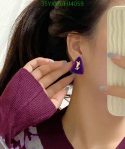 Woman showing purple earring in mirror selfie.