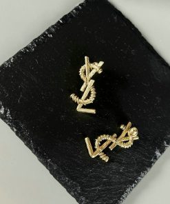 Gold designer cufflinks on black slate background.