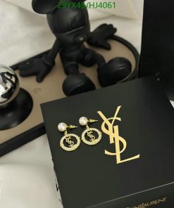 Designer earrings on YSL box with artistic figurine.