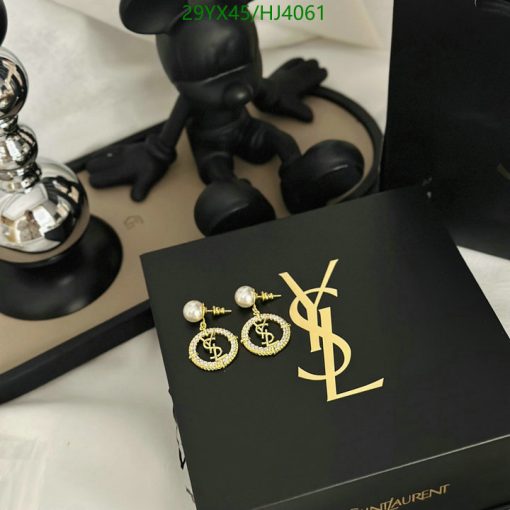 Designer earrings on YSL box with artistic figurine.