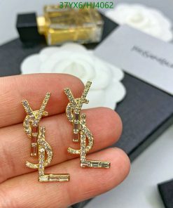 Gold diamond earrings on hand with perfume background.