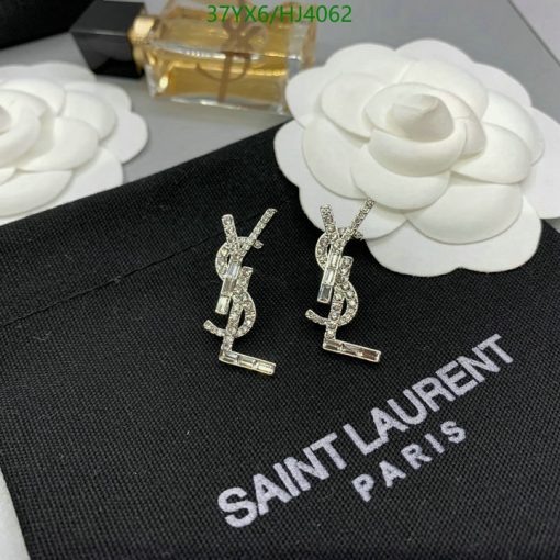 Diamond YSL logo earrings on black fabric.