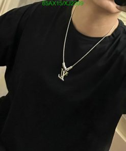 Man wearing black t-shirt with silver pendant necklace.