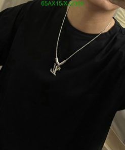 Person wearing black shirt with silver pendant necklace.