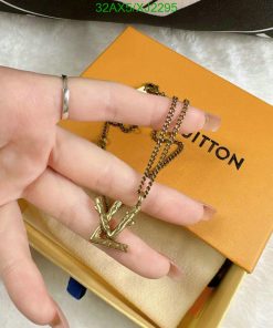 Hand displaying gold pendant necklace with branded box.