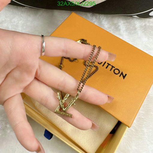 Hand displaying gold pendant necklace with branded box.