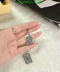 Person holding geometric pendant necklace with ring.