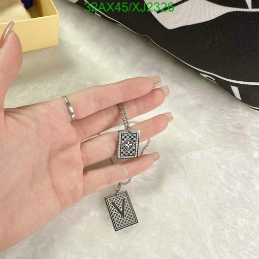 Person holding geometric pendant necklace with ring.