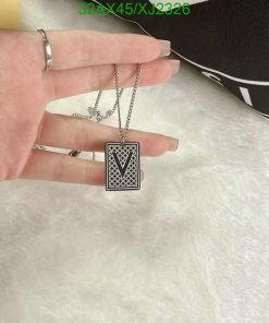 Hand holding V letter pendant over fuzzy background.